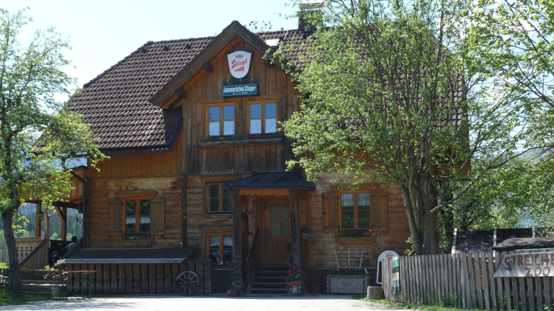 Ein traditionelles Holzhaus mit einem steilen Dach und zahlreichen Fenstern. Umgeben von Bäumen und einer einladenden Umgebung. | © Familie Pliem