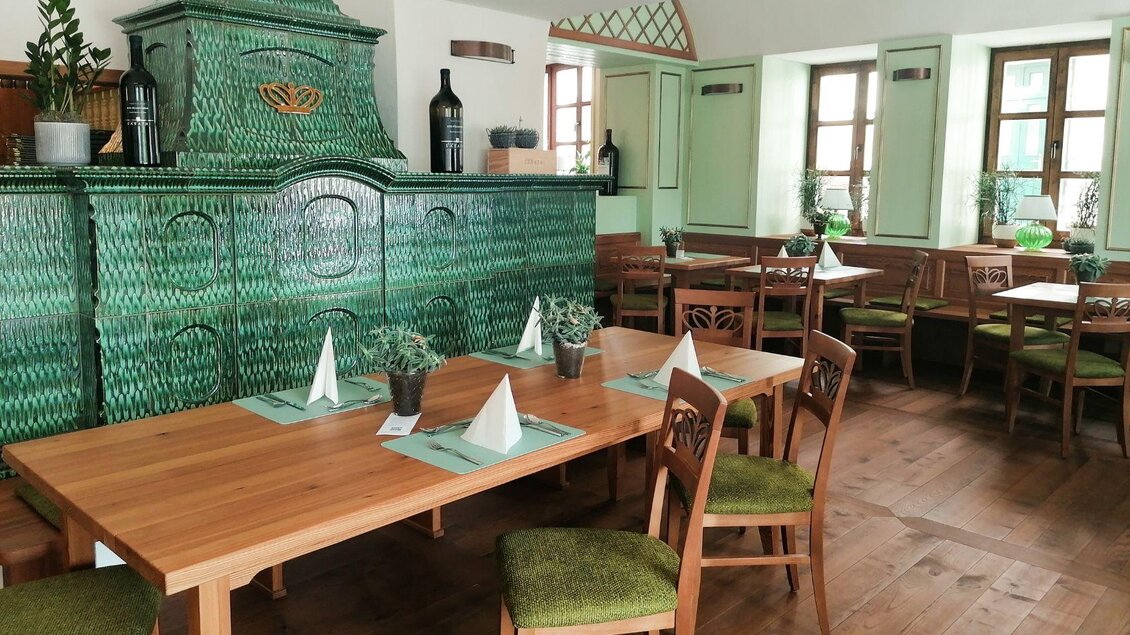 Das gemütliche Wirtshaus s`Johann mit Holztafeln und grünem Kachelofen. Die Fenster sind großzügig und bringen viel Tageslicht in den Raum. | © Wirtshaus s'Johann