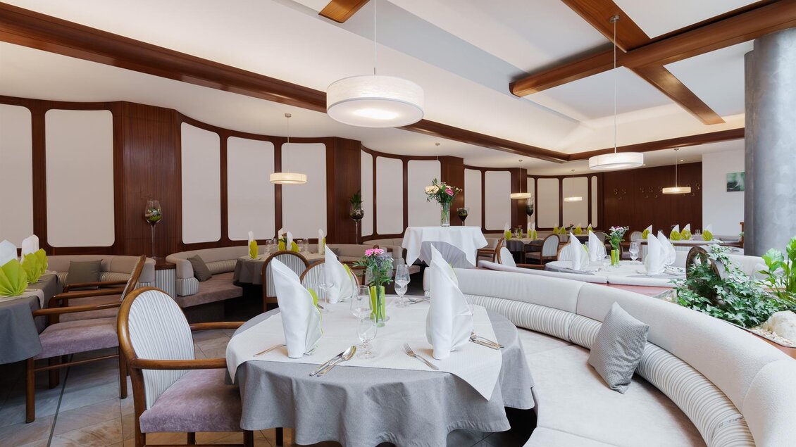 Ein elegantes Restaurant mit runden Tischen und geschmackvoller Dekoration. Helle Farben und eine gemütliche Atmosphäre schaffen ein einladendes Ambiente.