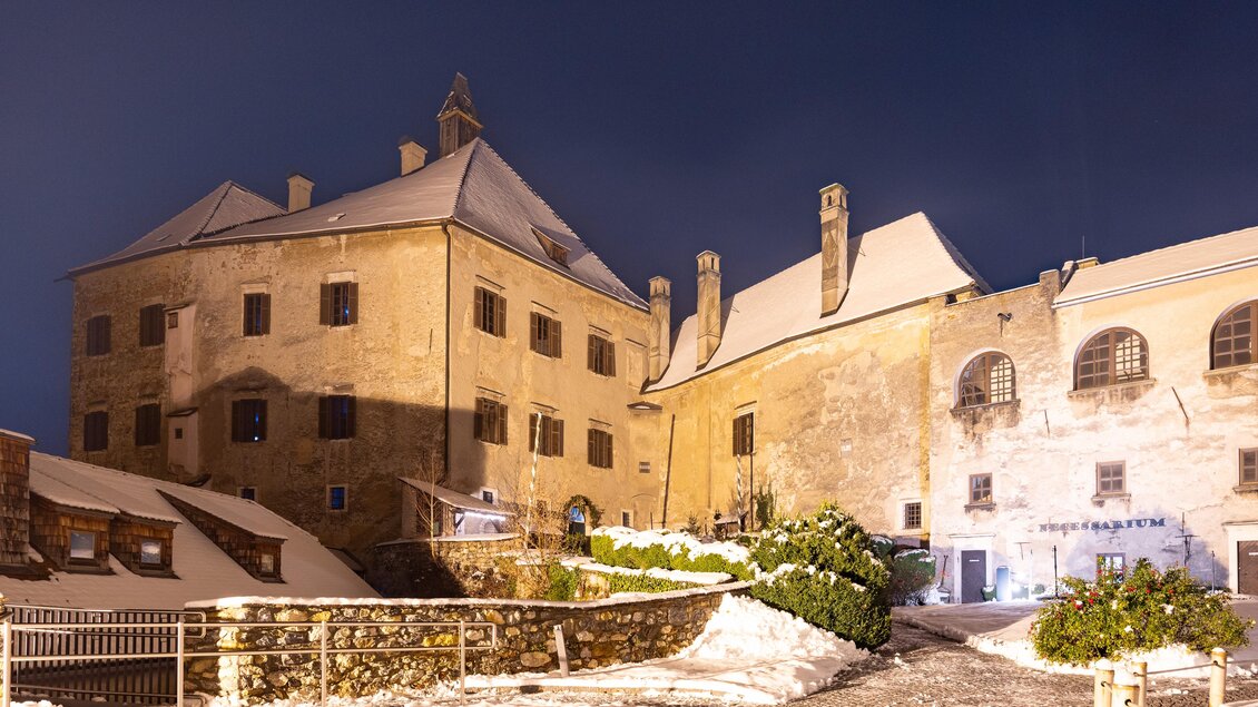 Eine historische Gebäudekomplex unter einem klaren Nachthimmel, umgeben von Schnee. Die Architektur zeigt charmante Details aus vergangener Zeit. | © Region Graz-Harry Schiffer
