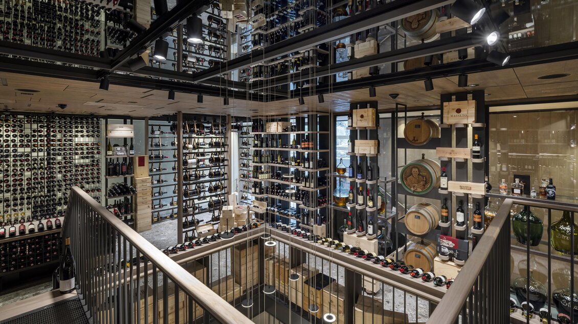 Ein eleganter Weinkeller mit Regalen voller Flaschen und einer modernen Einrichtung. Spiegel reflektieren die Weinregale und schaffen eine offene Atmosphäre. | © Pierer Gastronomie GmbH