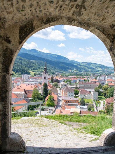 Das Bild zeigt den Blick auf die Stadt Bruck an der Mur mit vielen Dächern und der Pfarrkirche, vom Schlossberg hinunter