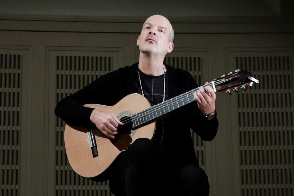 Ein Mann spielt Gitarre und sieht konzentriert aus. Der Hintergrund ist schlicht und hell.