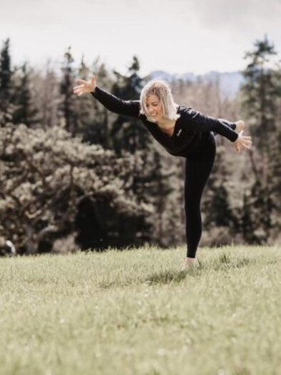 Eine Frau tanzt auf einer Wiese und balanciert im Freien. Im Hintergrund sind Bäume und ein bewölkter Himmel zu sehen. | © Erika Lange