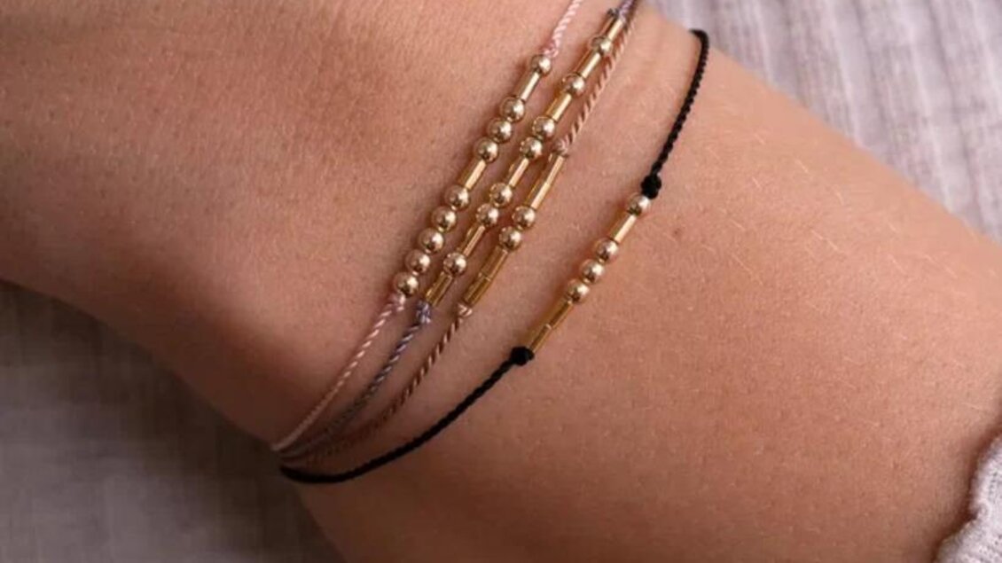 Ein Handgelenk mit mehreren zarten Armbändern in Gold- und Schwarzton. Die Armbänder haben unterschiedliche Designs und verleihen einen eleganten Look. | © @erikalange