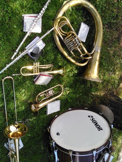 Eine Auswahl an Musikinstrumenten liegt auf grünem Gras. Darunter befinden sich eine Trompete, eine Posaune, eine Tuba, eine Flöte und ein Schlagzeug. | © Marlene Zandl