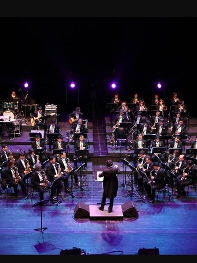 Ein großes Orchester spielt auf der Bühne. Der Dirigent steht vorne und leitet die Musiker in Abendbeleuchtung. | © Tourismus Oststeiermark