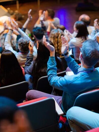 An audience applauds in an event space. The spectators are seated in rows and show enthusiasm for the presentation. | © AdobeStock_455882231