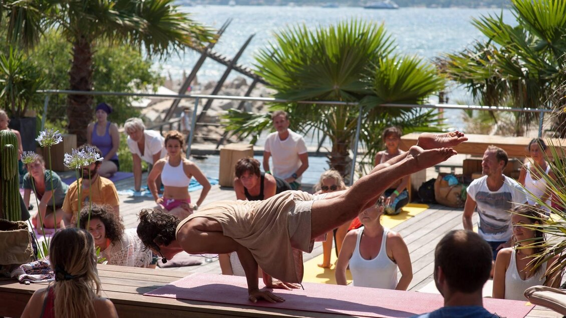 Yogalehrer demonstriert eine Arm-Balance vor Teilnehmern bei einem Yogaweekend im Freien auf einer Terrasse. | © Yogaweekend