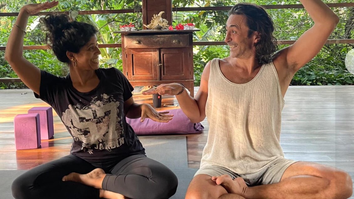 Beatrice und Mika sitzen im Schneidersitz und zeigen eine Handbewegung während eines Yogaweekends. | © Yogaweekend