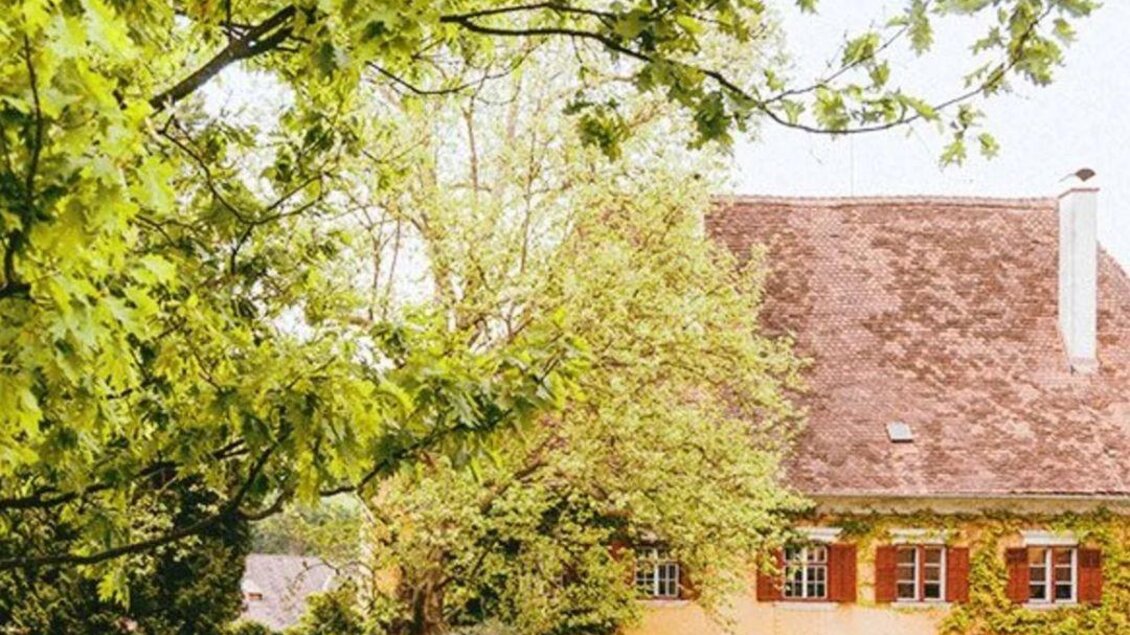 Ein schönes, gelb gestrichenes Haus umgeben von üppigem Grün. Der Garten hat einen gepflegten Rasen und einige Bäume. | © Tanja Muster | Schloss Ottersbach