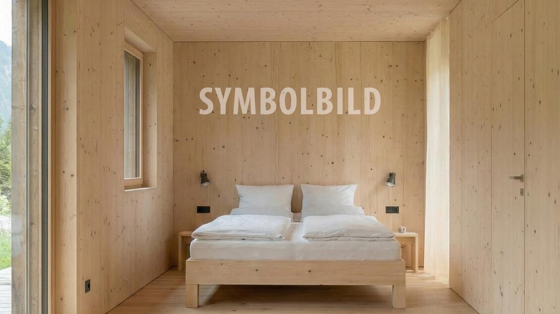 Ein helles Schlafzimmer mit Holzwänden und einem Doppelbett. Große Fenster sorgen für viel natürliches Licht und einen einladenden Raum.