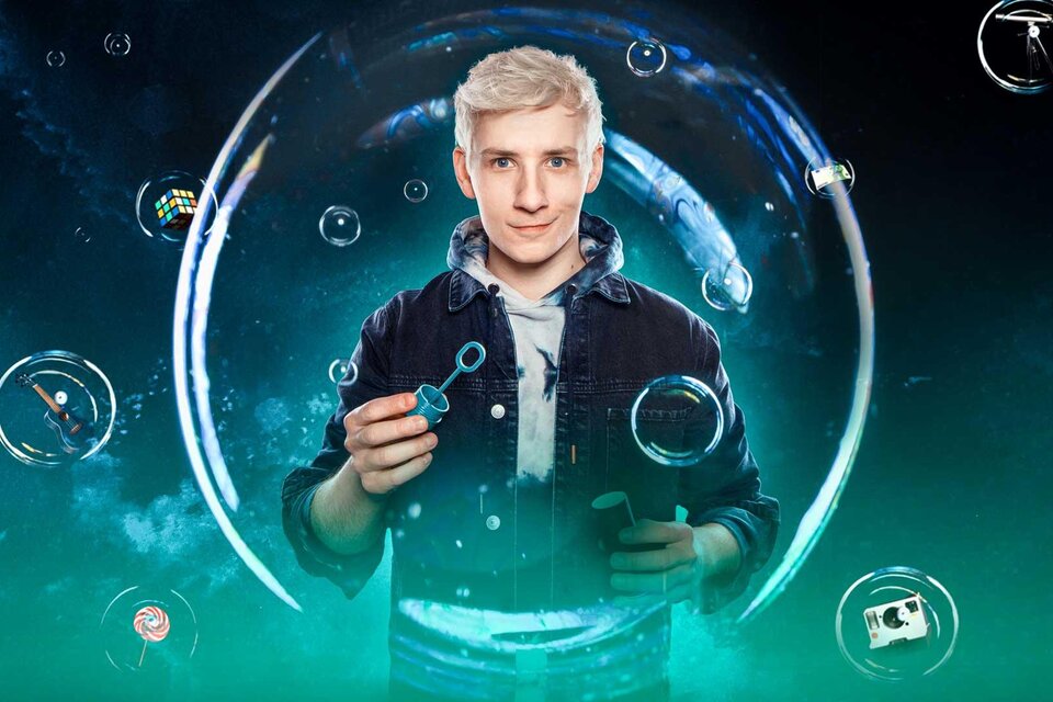 Ein junger Mann mit blonden Haaren lächelt freundlich in die Kamera. Der Hintergrund zeigt eine farbenfrohe, abstrakte Darstellung mit Blasen. | © Mellow