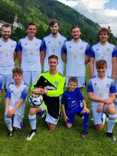Eine Fußballmannschaft posiert auf dem Spielfeld. Die Spieler tragen blaue und weiße Trikots und lächeln in die Kamera. | © USV Bretstein