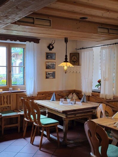 A cozy restaurant with wooden interiors and rustic tables. The walls are adorned with decorative panels and pictures. | © Petra Kirchschlager