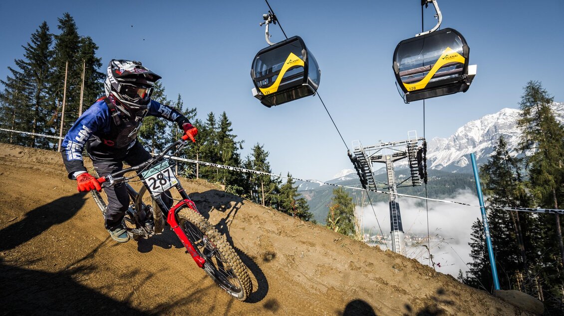 Downhill-Rennfahrer fährt eine Steilkurve auf einem Dirt-Trail unterhalb der Gondelbahn. | © Sebastian Gruber