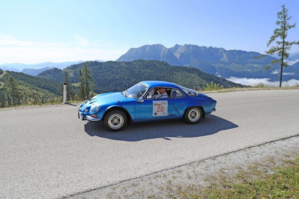 Ein blauer Sportwagen fährt eine kurvenreiche Straße entlang, umgeben von einer malerischen Berglandschaft. Der Himmel ist klar und die Aussicht ist beeindruckend. | © Ennstal-Classic_GEPA pictures_Mario Buehner