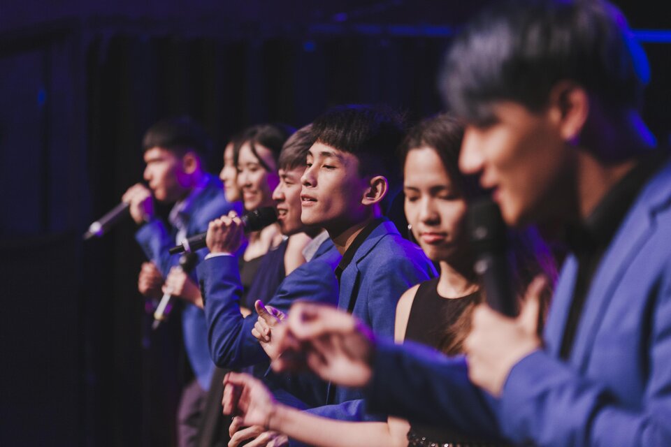 Eine Gruppe von Sängern steht auf der Bühne und präsentiert einen Auftritt. Sie tragen blaue Anzüge und konzentrieren sich auf ihre Darbietung. | © Stefan Lozar