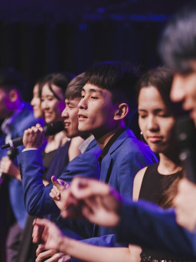 A group of singers stands on stage and presents a performance. They are wearing blue suits and are focused on their presentation. | © Stefan Lozar