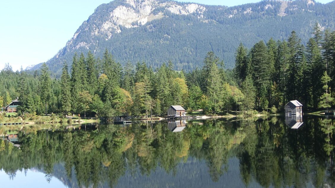 <p>Der ruhige Ödensee umgeben von dichtem Wald und den Bergen des Ausseerlandes. Die Hütten spiegeln sich im klaren Wasser.</p> | © TVB Ausseerland Salzkammergut-Tom Lamm