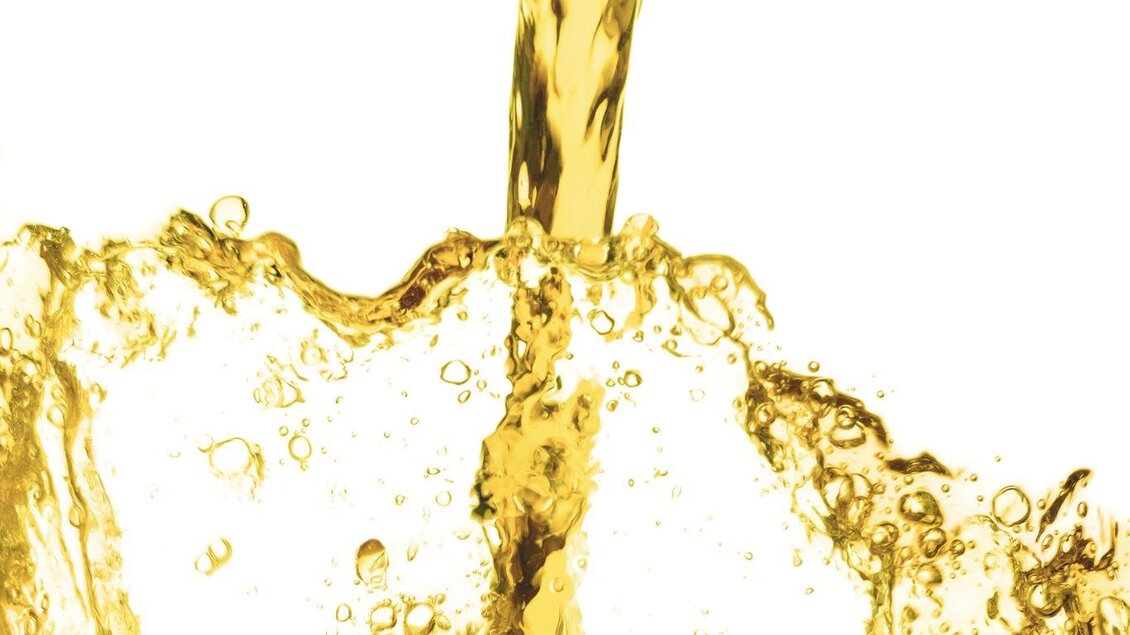 Ein Fluss flüssiges Gold, das in eine Pfütze spritzt. Die sprudelnden Blasen erzeugen einen lebhaften Effekt. | © Ölmühle Fandler