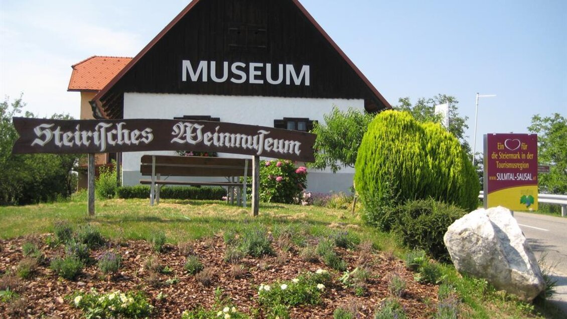 Ein Museum mit dem Namen "Steirisches Weinmuseum" in ländlicher Umgebung. Der Gebäude hat ein traditionelles Design und ist von grünen Pflanzen umgeben. | © TV Südsteiermark