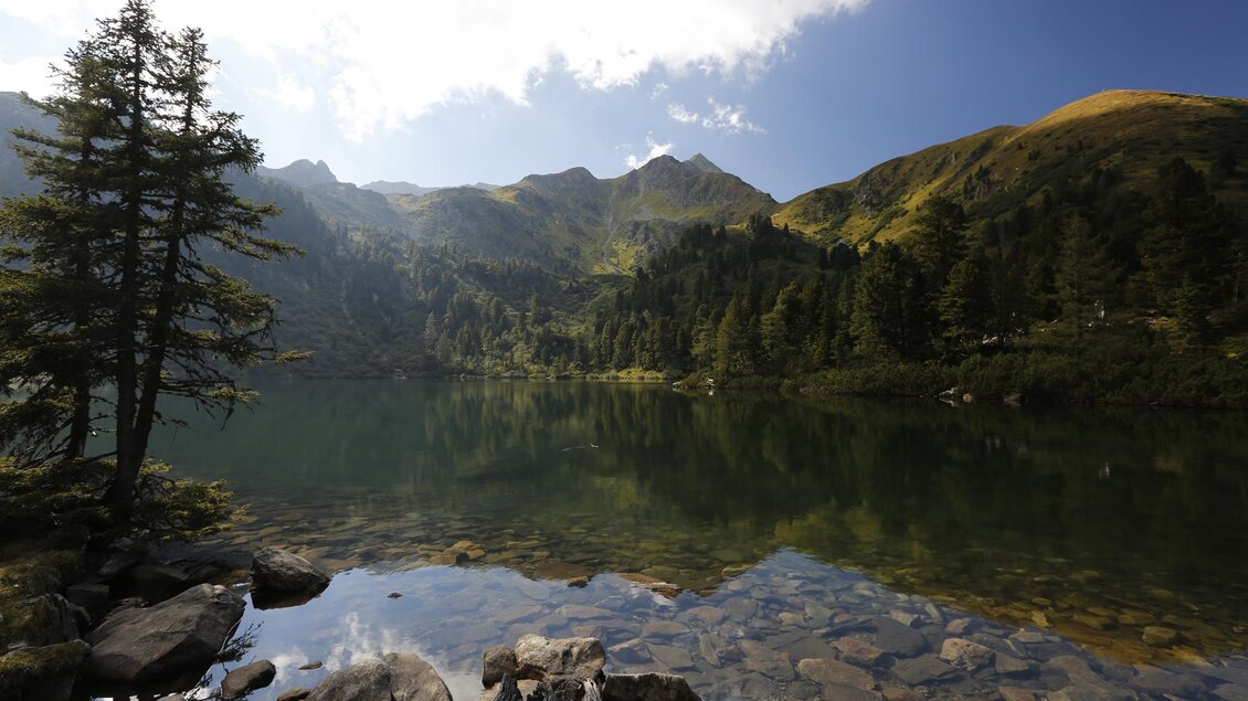 Ein ruhiger Bergsee, umgeben von grünen Wäldern und Bergen. Der Himmel ist blau mit einigen Wolken. | © Erlebnisregion Murtal