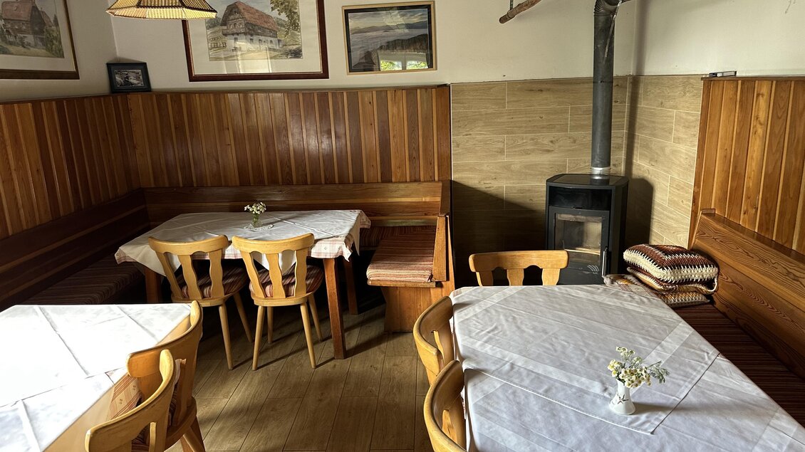 Ein gemütliches Restaurant mit Holztischen und Bänken. An den Wänden hängen Bilder von ländlichen Motiven. | © TV Hochsteiermark
