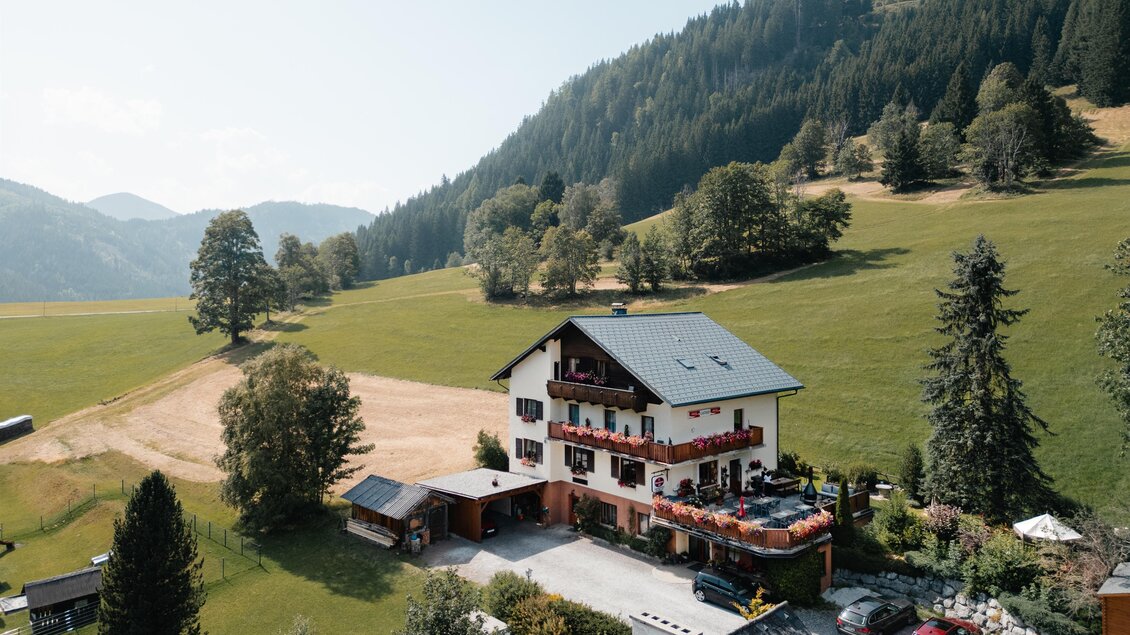 Ein schönes Gebäude mit Balkon, geschmückt mit bunten Blumen. Im Hintergrund sind grüne Berge zu sehen. | © TV Gesäuse