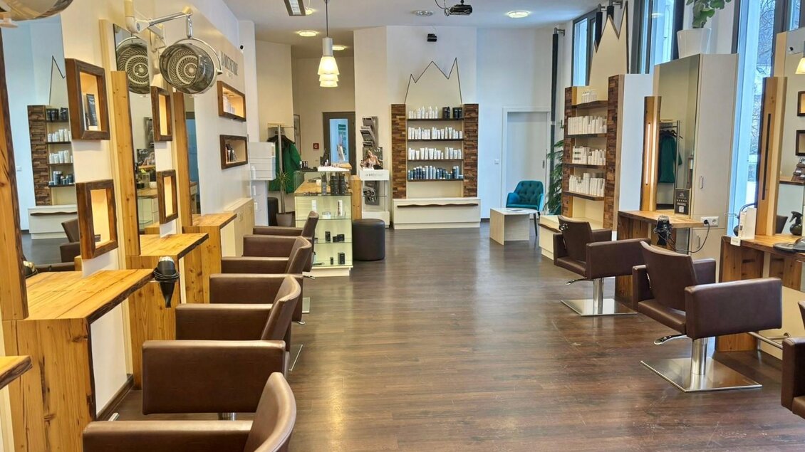 Ein moderner Friseursalon mit Holzregalen und bequemen Stühlen. Das Ambiente ist hell und einladend. | © Alpenhaar Bad Aussee