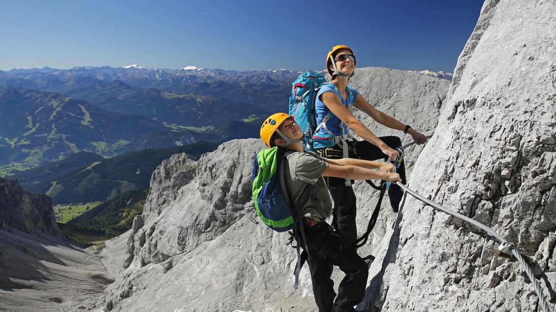 Zwei Kletterer erkunden eine steile Felswand in den Alpen. Umgeben von einer atemberaubenden Berglandschaft genießen sie das Abenteuer in der Natur. | © Alpincenter Dachstein