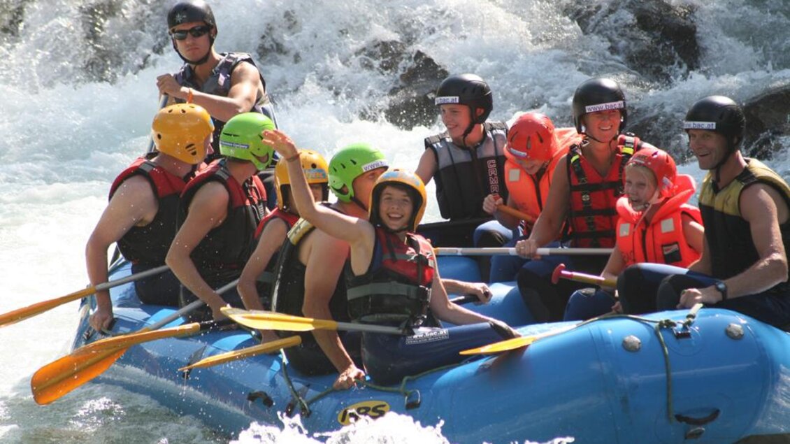 Eine Gruppe von Menschen beim Rafting auf einem Wildwasserbach. Alle tragen Schwimmwesten und Helme, während sie gemeinsam paddeln. | © Alpincenter Dachstein