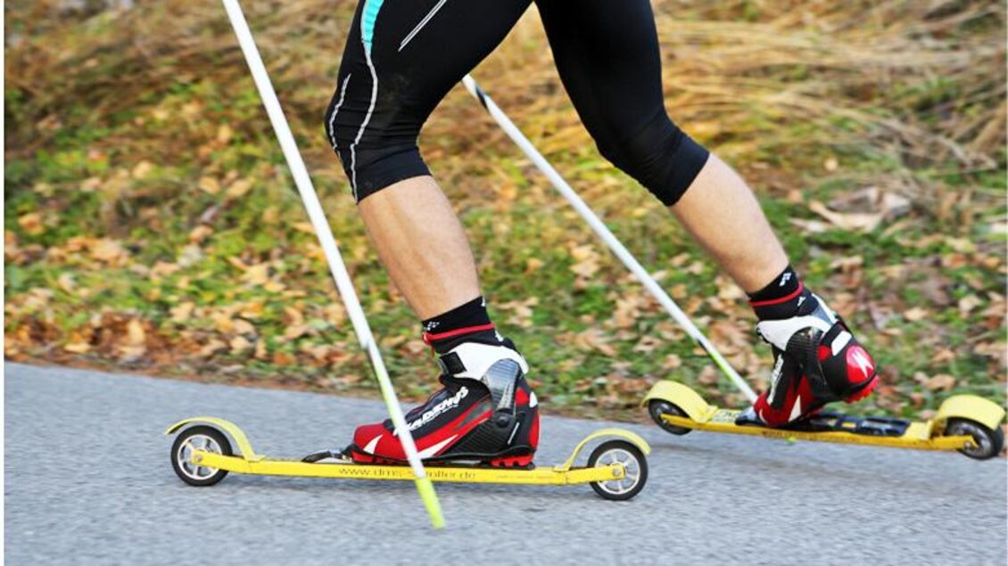 Eine Person fährt mit Rollskiern auf einer Straße. Die Beine sind in sportlicher Kleidung und in Bewegung. | © Alpincenter Dachstein