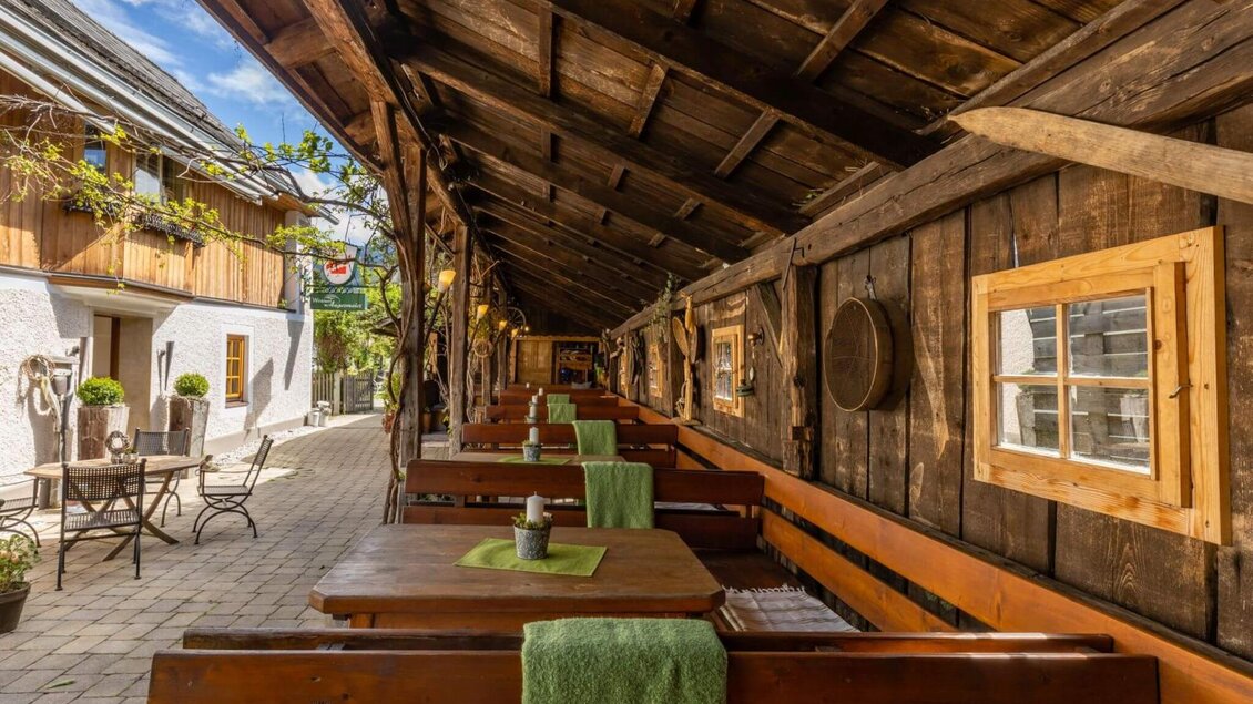 Überdachter Gastgarten mit Holzbänken und Tischen in rustikalem Ambiente. | © Gasthaus Angermaier