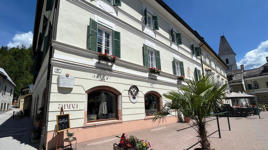 Das historische Meranhaus am Meranplatz in Bad Aussee mit bunten Blumen und einer Palme vor dem Geschäft | © TVB Ausseerland Salzkammergut_Nathalie Schröttenhamer