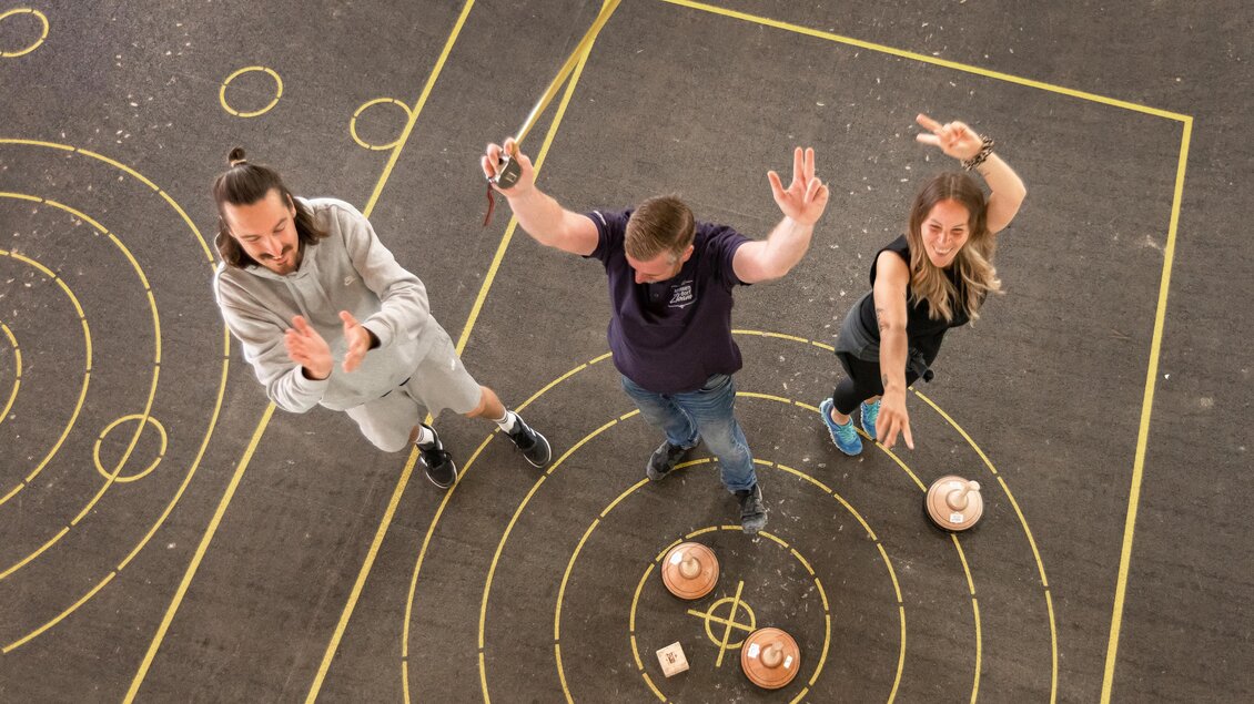 Drei Personen stehen in einem Spielbereich und posieren mit lässigen Gesten. Sie scheinen an einem Spiel oder Wettbewerb teilzunehmen. | © Narzissendorf Zloam, www.zloam.at