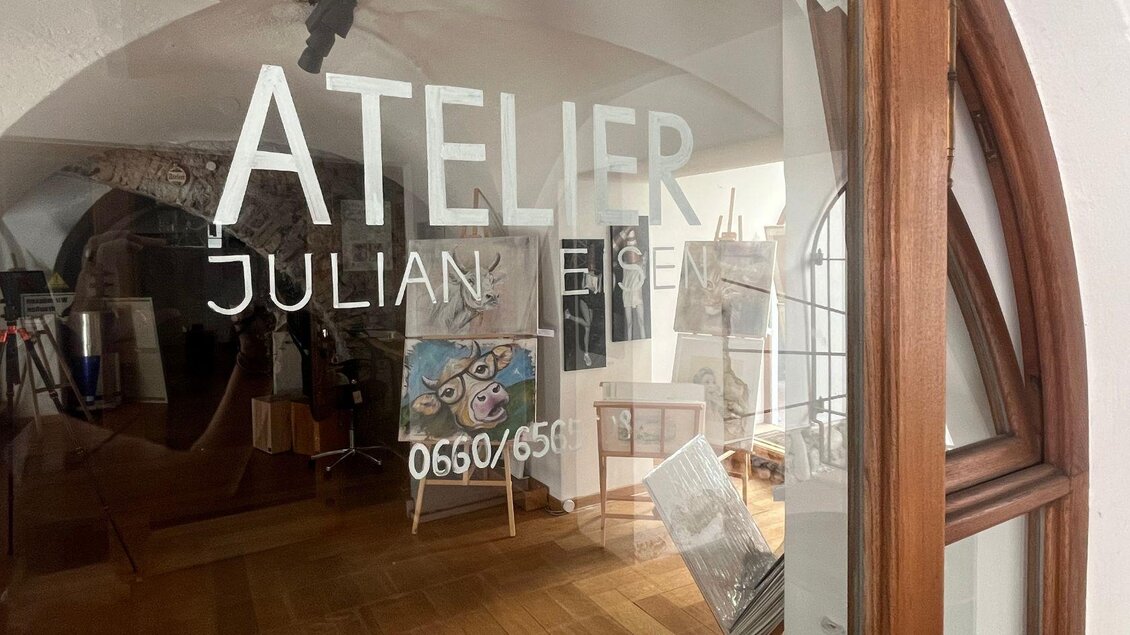 Ein Atelier mit dem Namen "Julian Eisen". Durch das Fenster sind Bilder und Malutensilien sichtbar. | © TVB Ausseerland Salzkammergut_Nathalie Schröttenhamer