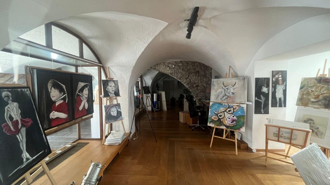 Ein Kunstraum mit mehreren Gemälden an den Wänden und Staffeleien. Die Umgebung hat einen modernen und einladenden Eindruck. | © TVB Ausseerland Salzkammergut_Nathalie Schröttenhamer