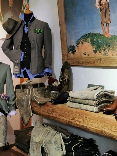 A cozy clothing store with traditional garments, including jackets and pants. There are also stylish shoes and a beautiful mural in the background. | © Alexander Greul