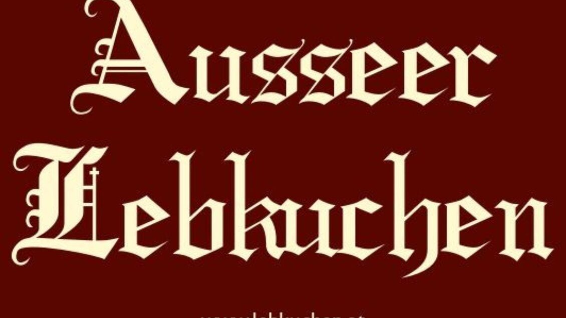Ein rotes Schild mit der Aufschrift „Ausseer Lebkuchen“ in dekorativer Schrift. Darunter befindet sich die Website „www.lebkuchen.at“. | © Ausseer Lebkuchen