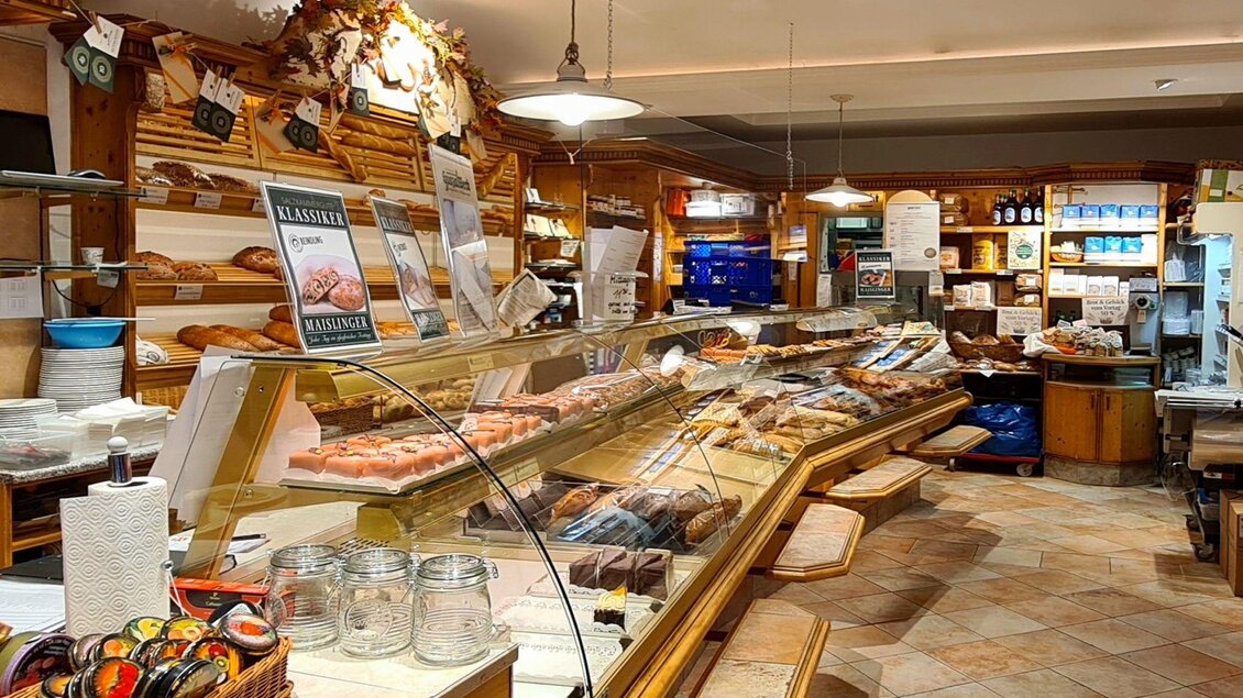 Ein gemütlicher Lebensmittelladen mit Holzregalen und vielen verschiedenen Leckereien. Die Vitrine zeigt eine Auswahl an frischen Bäckereiprodukten. | © Stephanie Bor