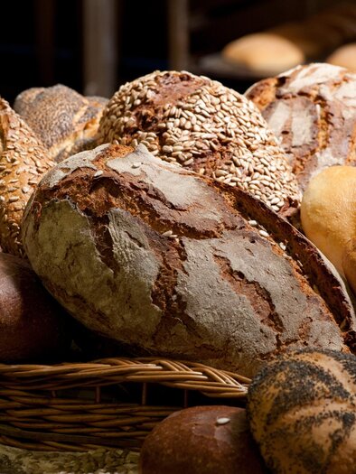 Eine Auswahl von verschiedenen Brotsorten liegt auf einem Tisch. Die Brote haben unterschiedliche Formen und werden durch eine rustikale Präsentation hervorgehoben. | © AdobeStock_33682785-travelguide