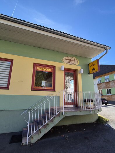 Ein buntes Gebäude mit einer Treppe und einem Schaufenster. Im Hintergrund sind weitere Häuser sichtbar. | © TVB Murau