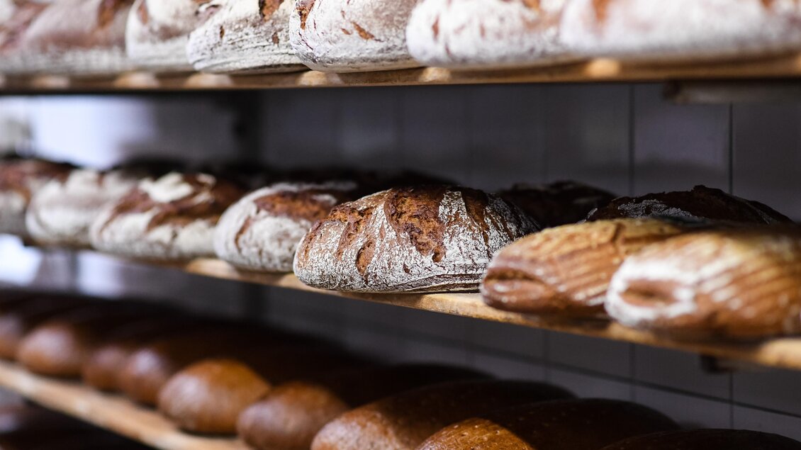 Eine Bäckerei mit verschiedenen Brotsorten auf Holzregalen. Die Brote sind frisch gebacken und zeigen eine appetitliche Kruste. | © Günter Ludwig Kämmerer