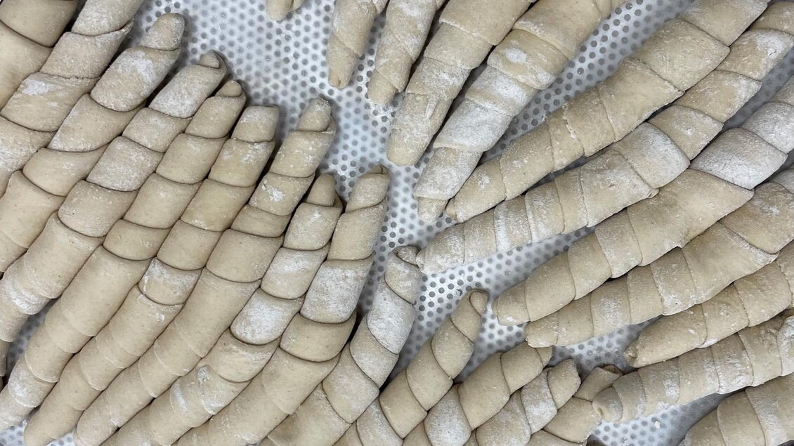 Eine Ansammlung von geformten Teigstücken, die bereit zum Backen sind. Die Oberfläche ist leicht bemehlt und zeigt eine geschwungene Form. | © Bäckerei Steffl-Bäck