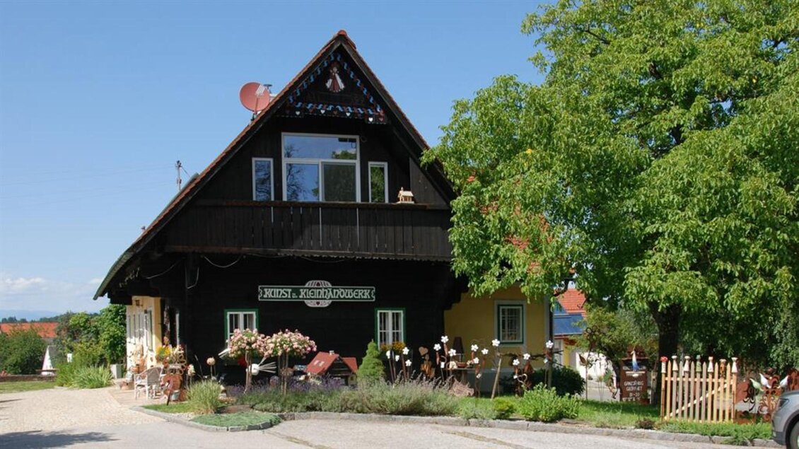 Ein charmantes, traditionelles Holzhaus mit einem grünen Garten. Die Umgebung ist hell und sonnig, ideal für einen ruhigen Aufenthalt. | © Bäuerliches Kunst- und Kleinhandwerk