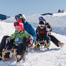 A family is going down the toboggan run with two sleds. | © Tourismusverband Murau