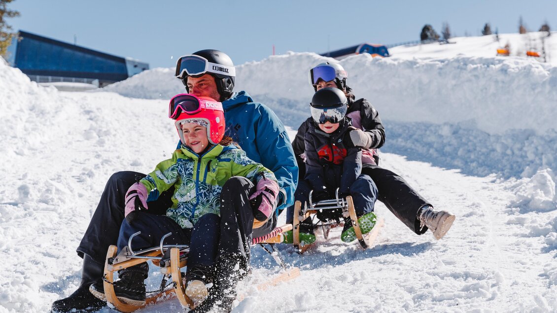 Eine Familie fährt mit zwei Schlitten die Rodelstrecke hinunter. | © Tourismusverband Murau