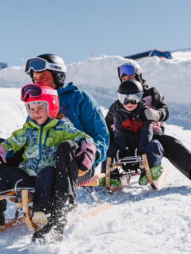 A family is going down the toboggan run with two sleds. | © Tourismusverband Murau