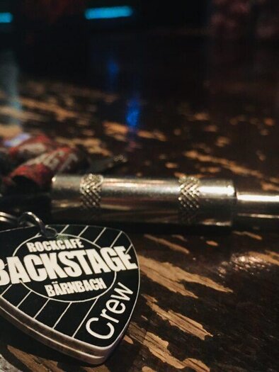 Plektrum und Schlüsselbund auf Holztisch im Backstage-Bereich des Rockcafés Bärnbach in der Steiermark. | © Homepage Backstage